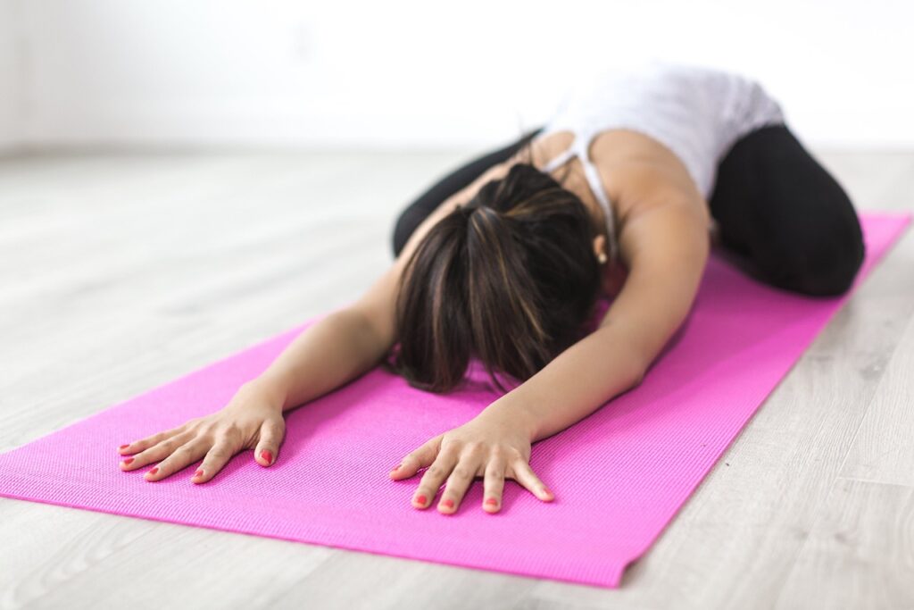 Woman doing a yoga asana on the pink mat.