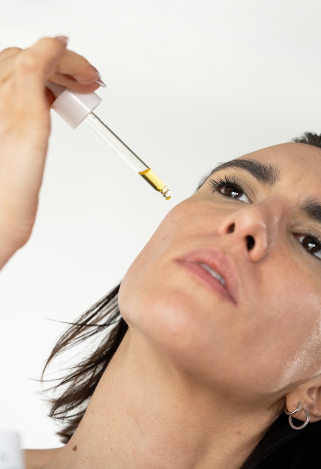 Woman dripping oil on her face for her facial massage beauty ritual.