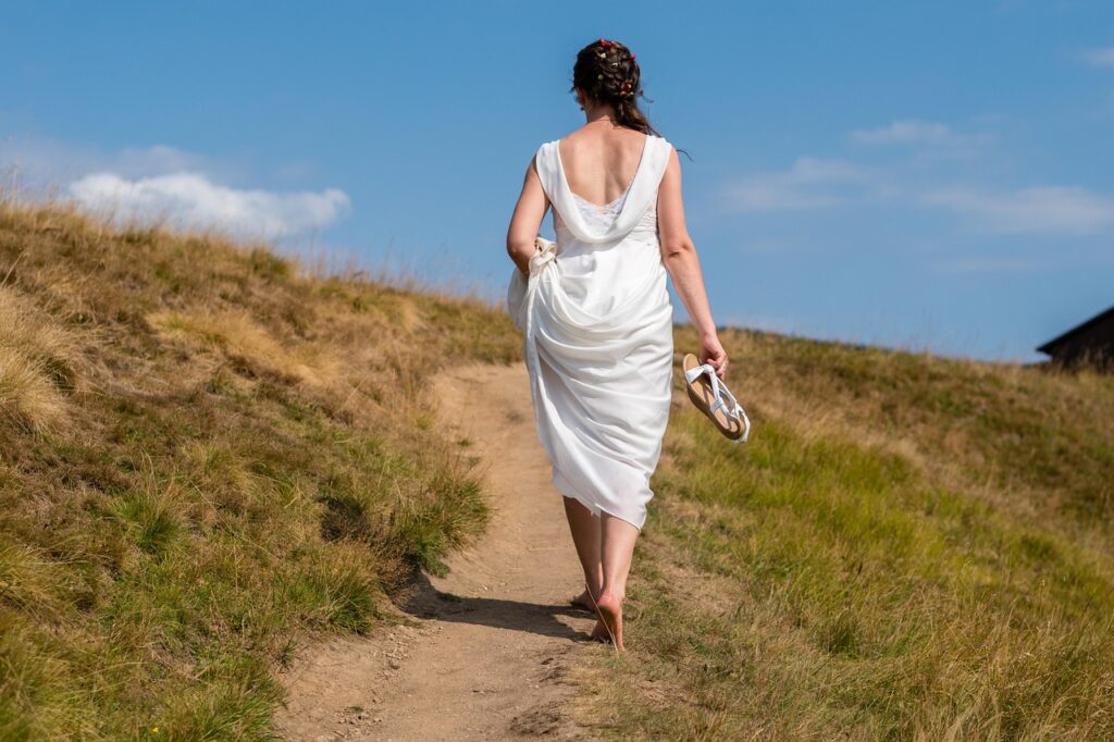 A woman walking barefoot in nature, practicing grounding.