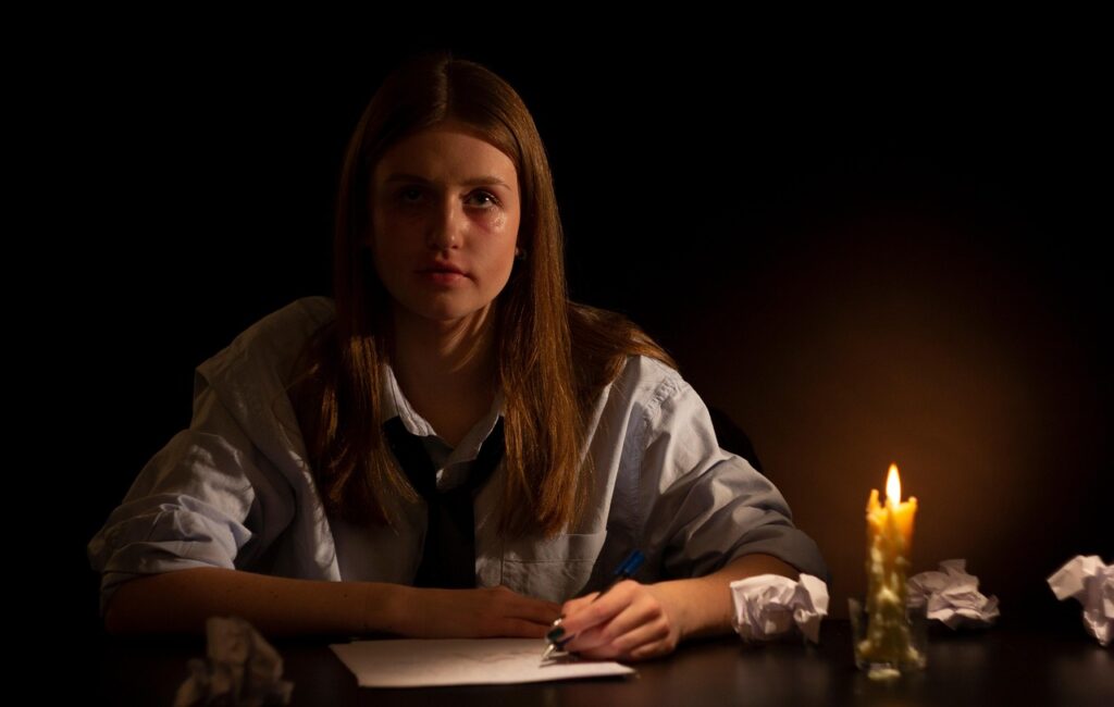 Woman writing down her feelings to later burn them in the transmutation ritual. This is one of Energy Cleansing Rituals.